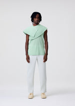 A model wears the HOMME PLISSÉ ISSEY MIYAKE TAILORED PLEATS 3 tailored-pleats-3-trousers-genova-metal-ochre.