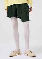 A model wears the HOMME PLISSÉ ISSEY MIYAKE PAINTER'S GEAR trousers.