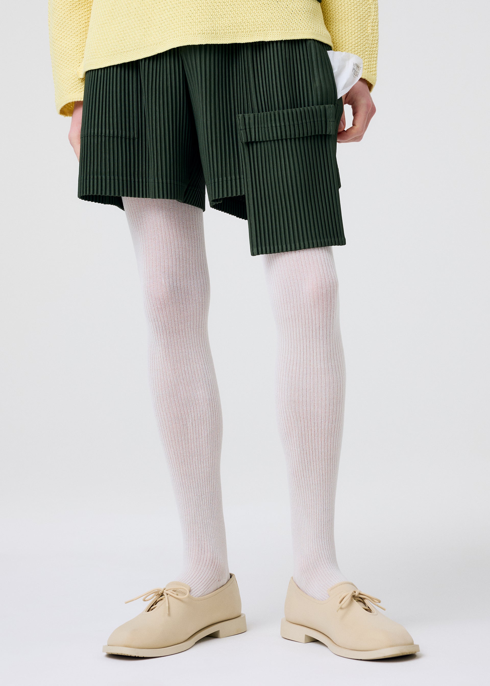 A model wears the HOMME PLISSÉ ISSEY MIYAKE PAINTER'S GEAR trousers.