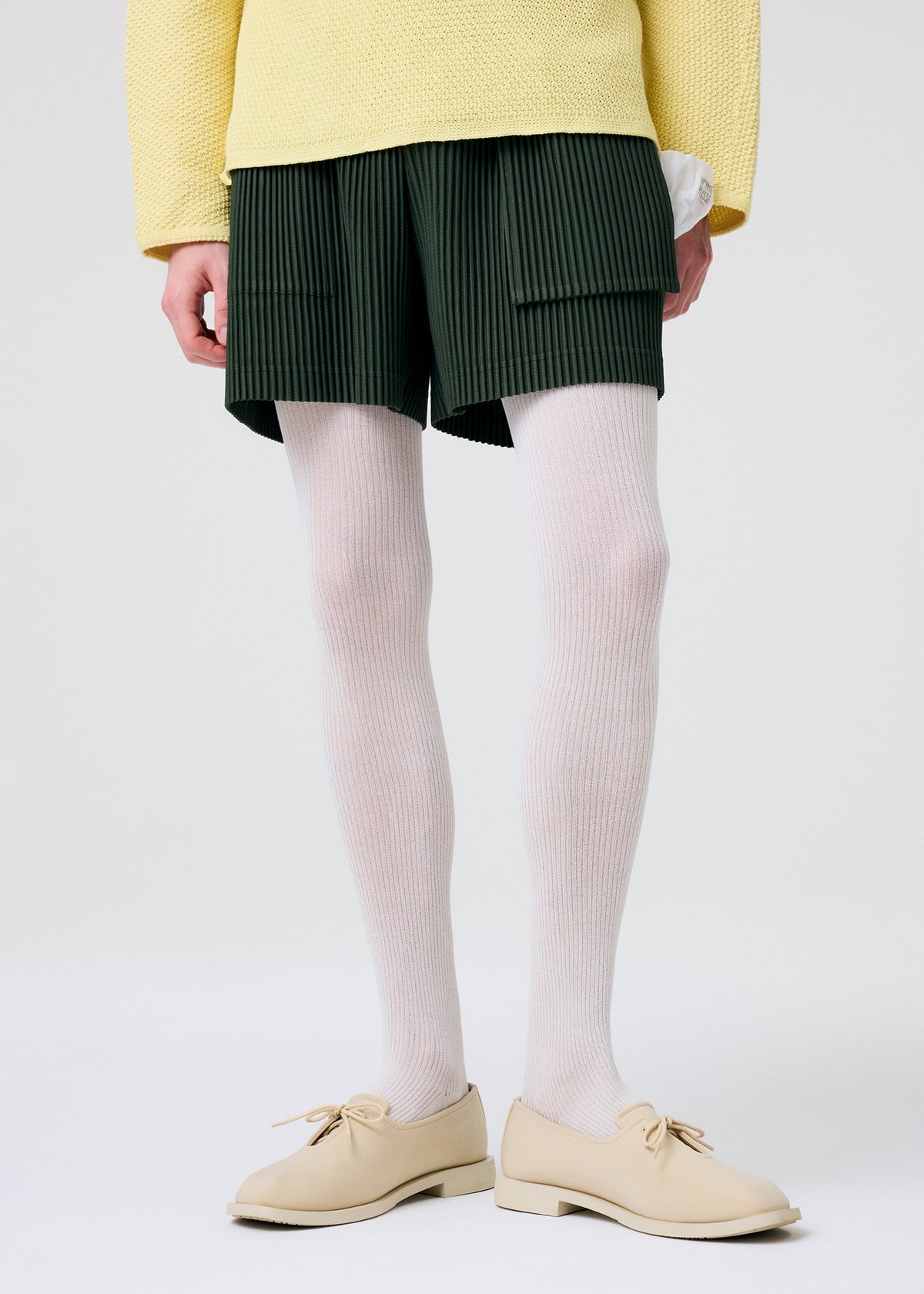 A model wears the HOMME PLISSÉ ISSEY MIYAKE PAINTER'S GEAR trousers.