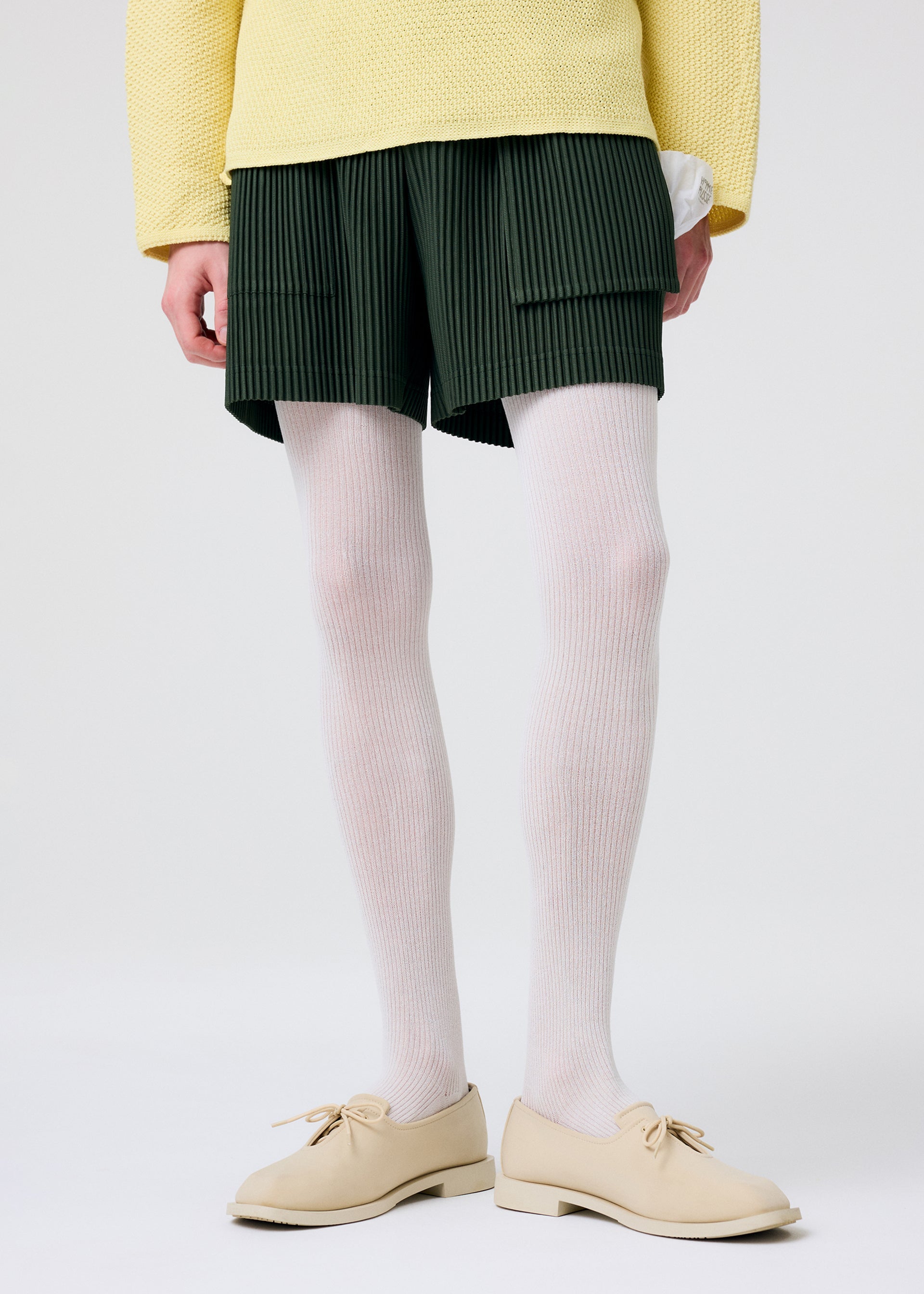 A model wears the HOMME PLISSÉ ISSEY MIYAKE PAINTER'S GEAR trousers.