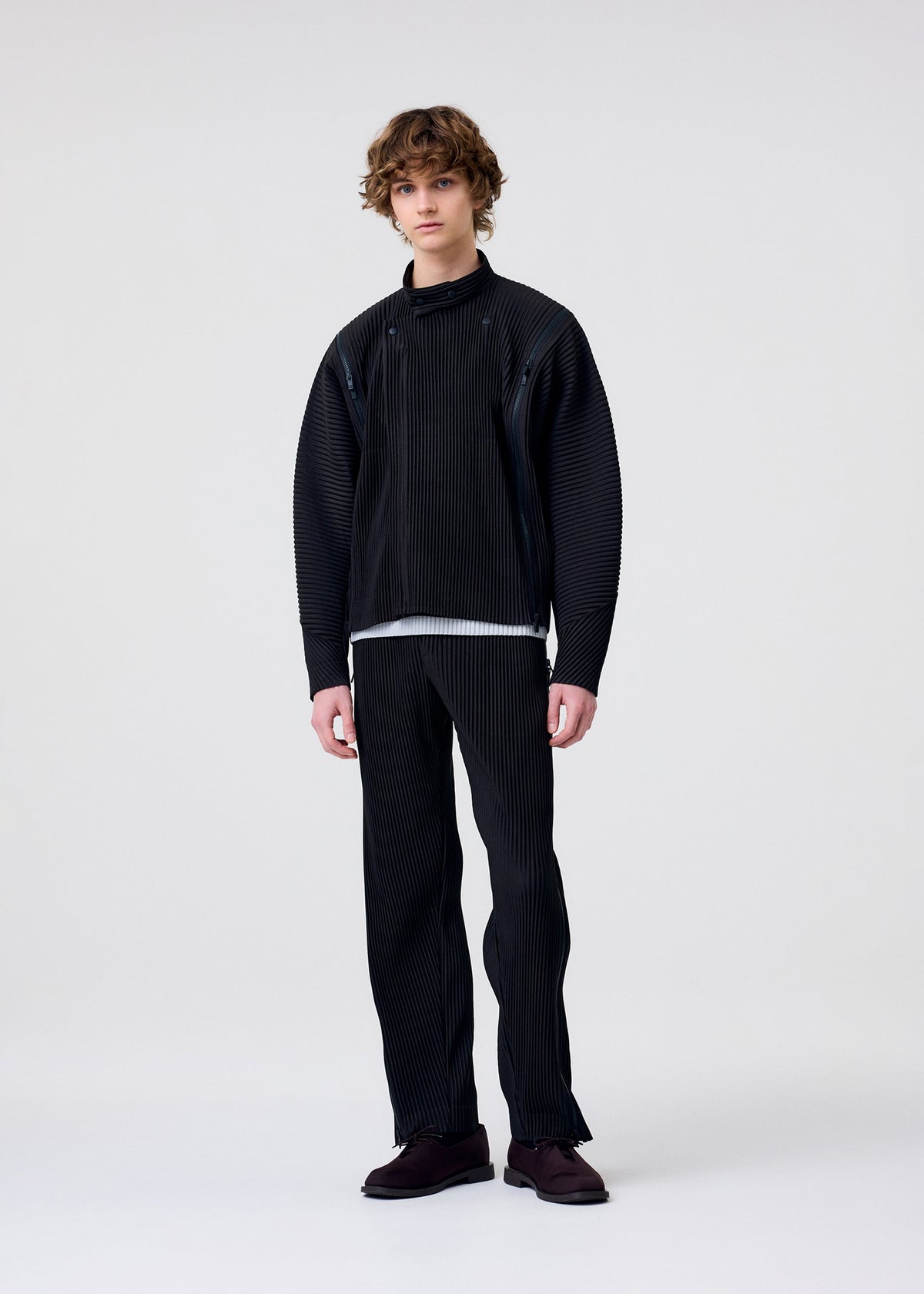 A model wears the HOMME PLISSÉ ISSEY MIYAKE MULTI-FASTENED multi-fastened-trousers-lucca-storico-blue.
