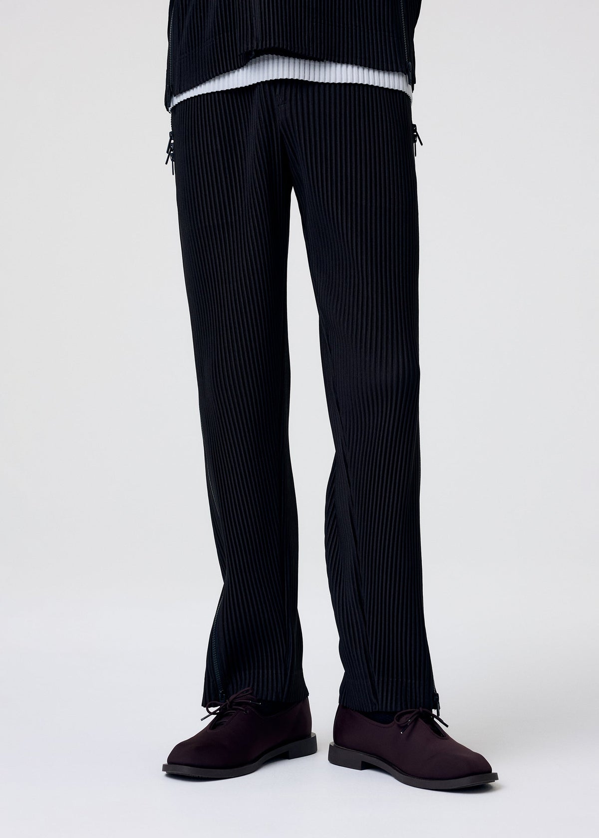 A model wears the HOMME PLISSÉ ISSEY MIYAKE MULTI-FASTENED multi-fastened-trousers-lucca-storico-blue.