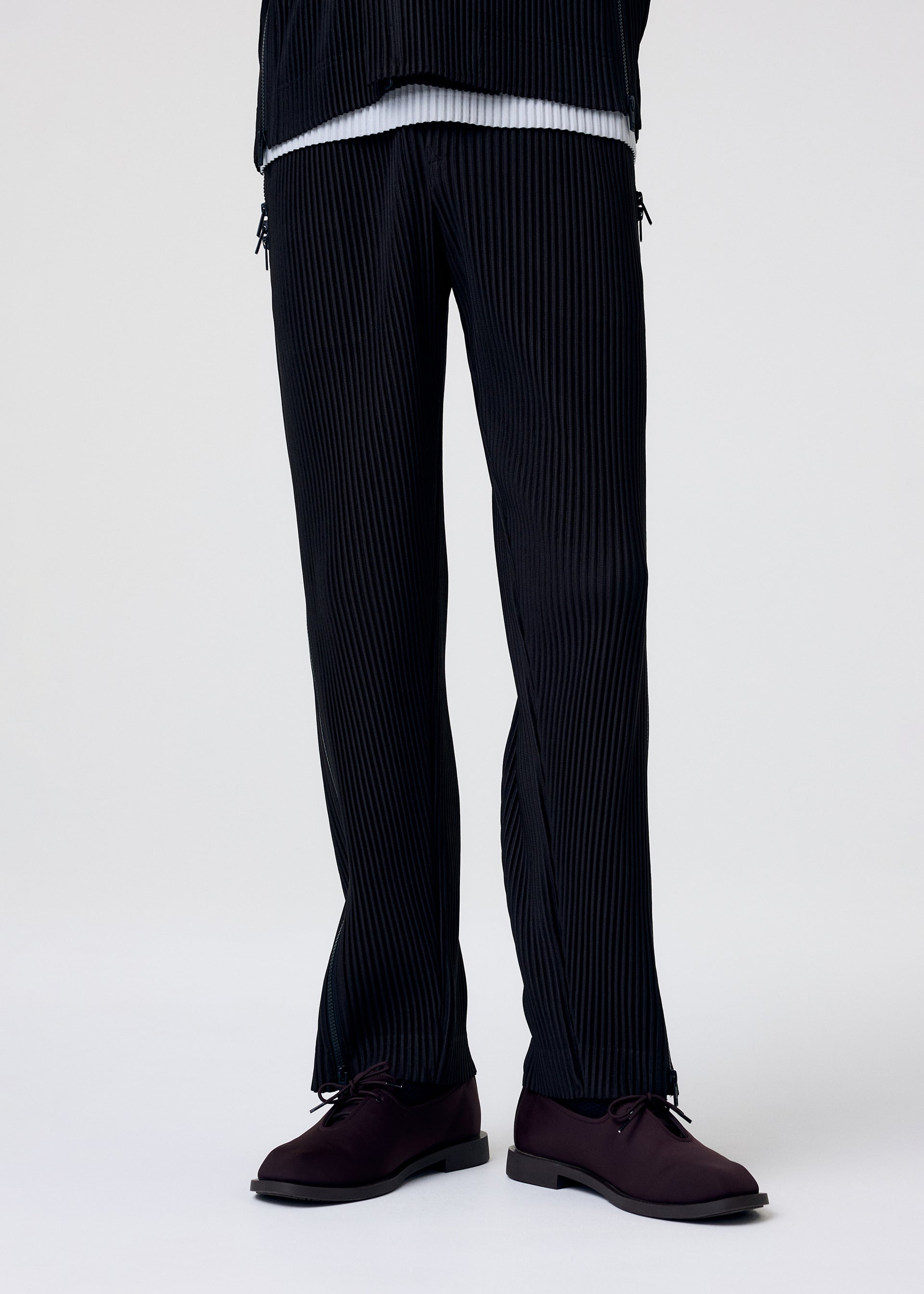 A model wears the HOMME PLISSÉ ISSEY MIYAKE MULTI-FASTENED multi-fastened-trousers-lucca-storico-blue.