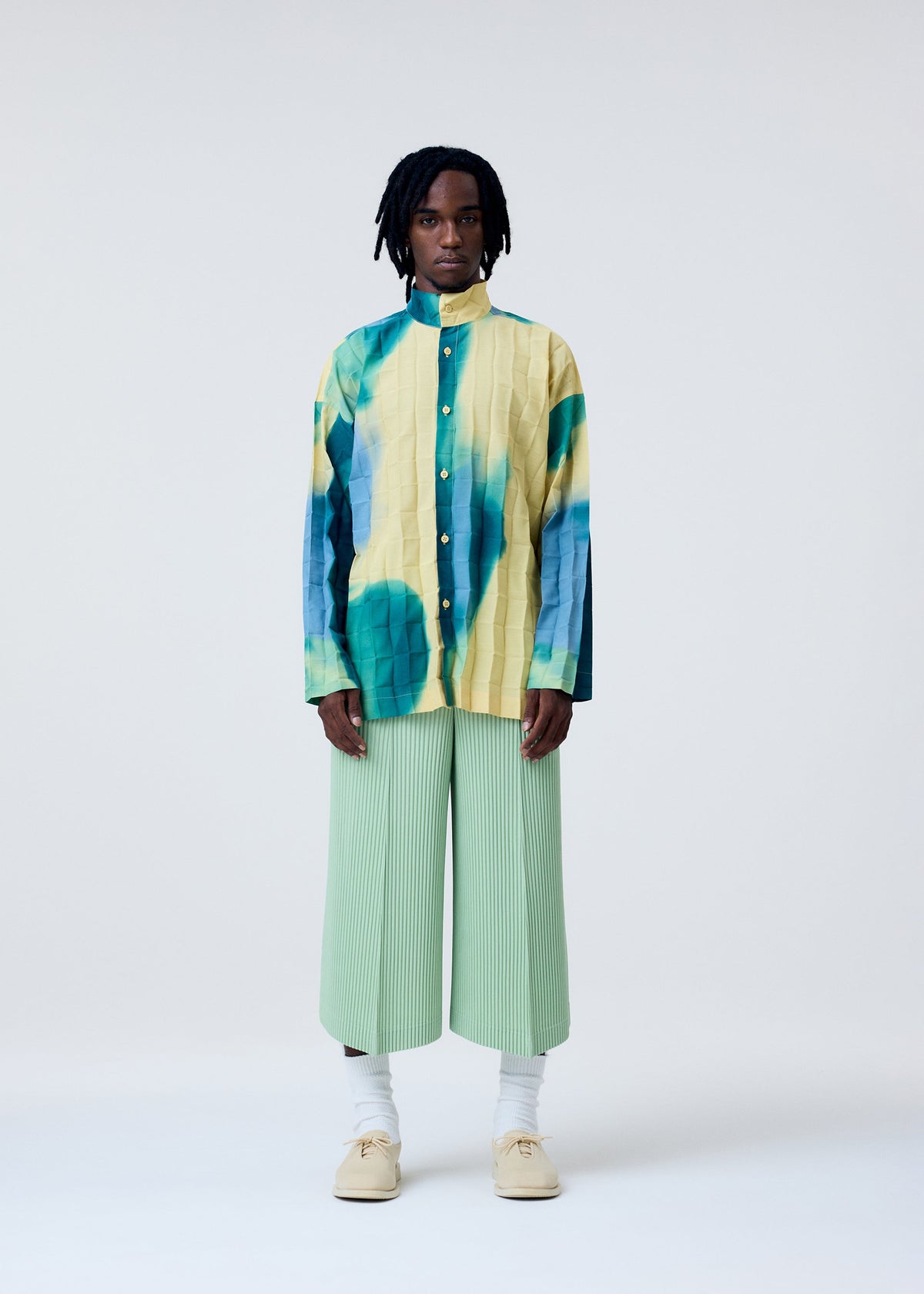 A model wears the HOMME PLISSÉ ISSEY MIYAKE PLEATS BOTTOMS 2 trousers.