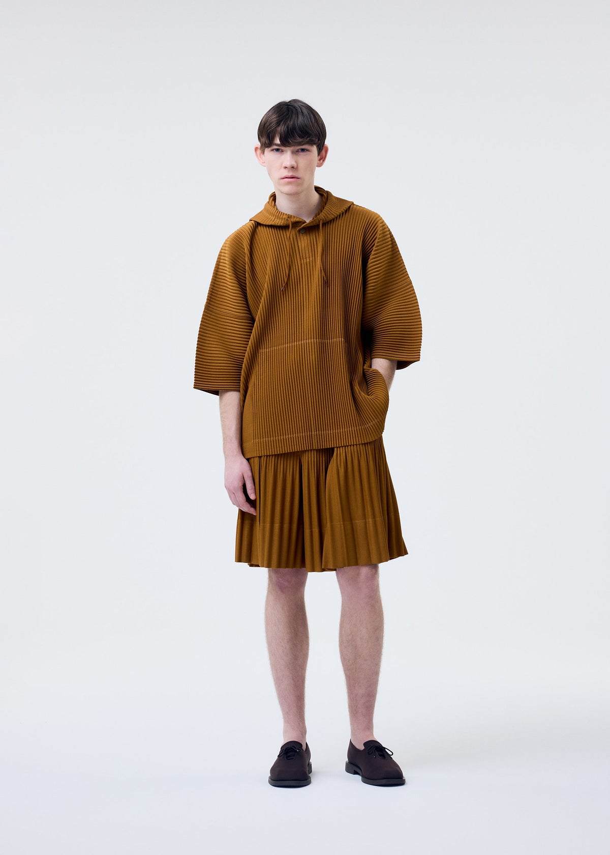 A model wears the HOMME PLISSÉ ISSEY MIYAKE MONTHLY COLORS : JUNE monthly-colors-june-top-genova-metal-ochre-1.