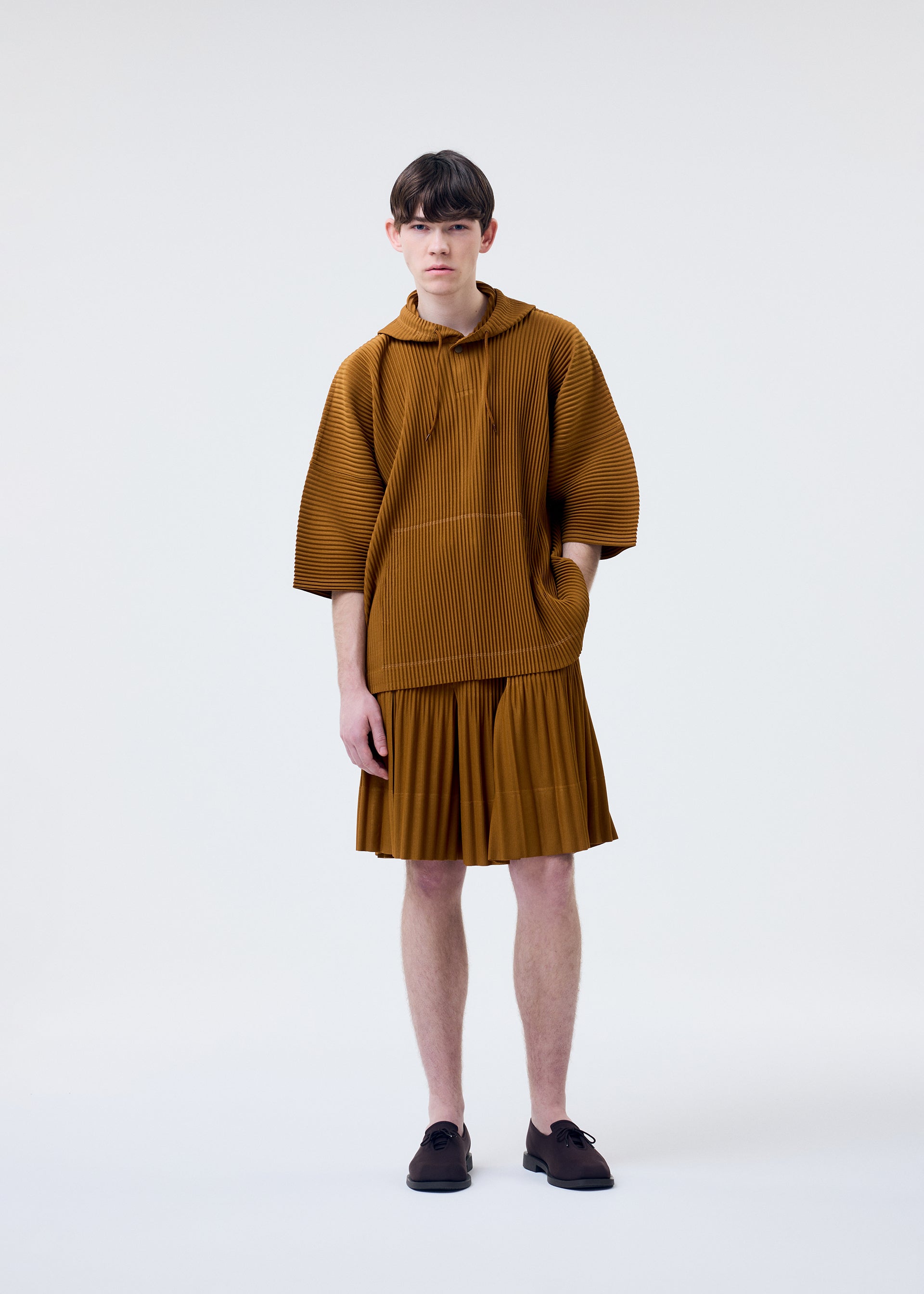 A model wears the HOMME PLISSÉ ISSEY MIYAKE MONTHLY COLORS : JUNE monthly-colors-june-top-venice-boat-brown-1.