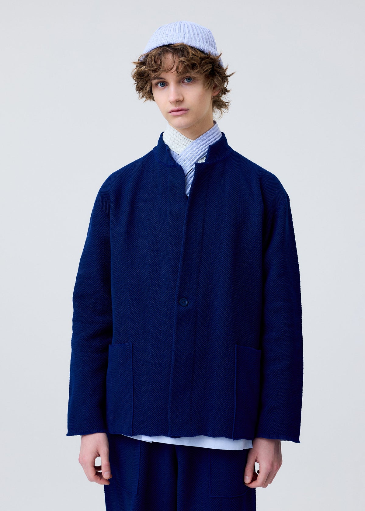 A model wears the HOMME PLISSÉ ISSEY MIYAKE INLAID KNIT jacket.