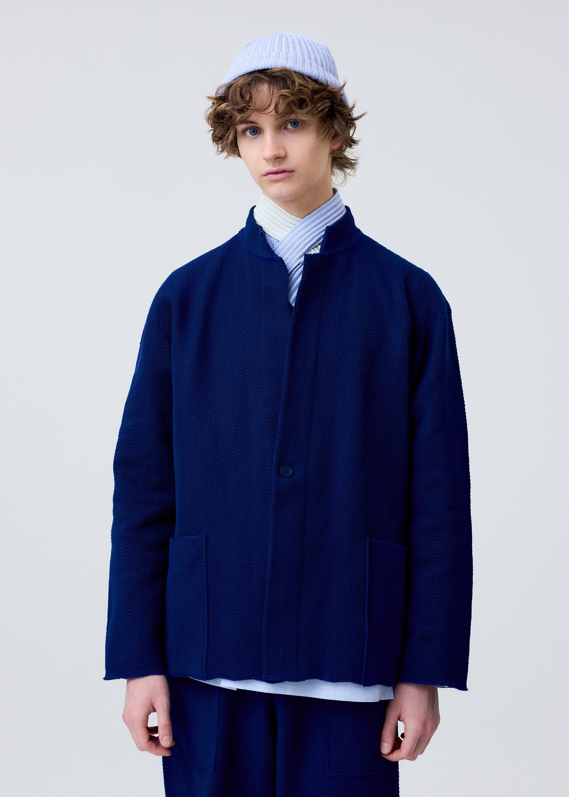 A model wears the HOMME PLISSÉ ISSEY MIYAKE INLAID KNIT jacket.