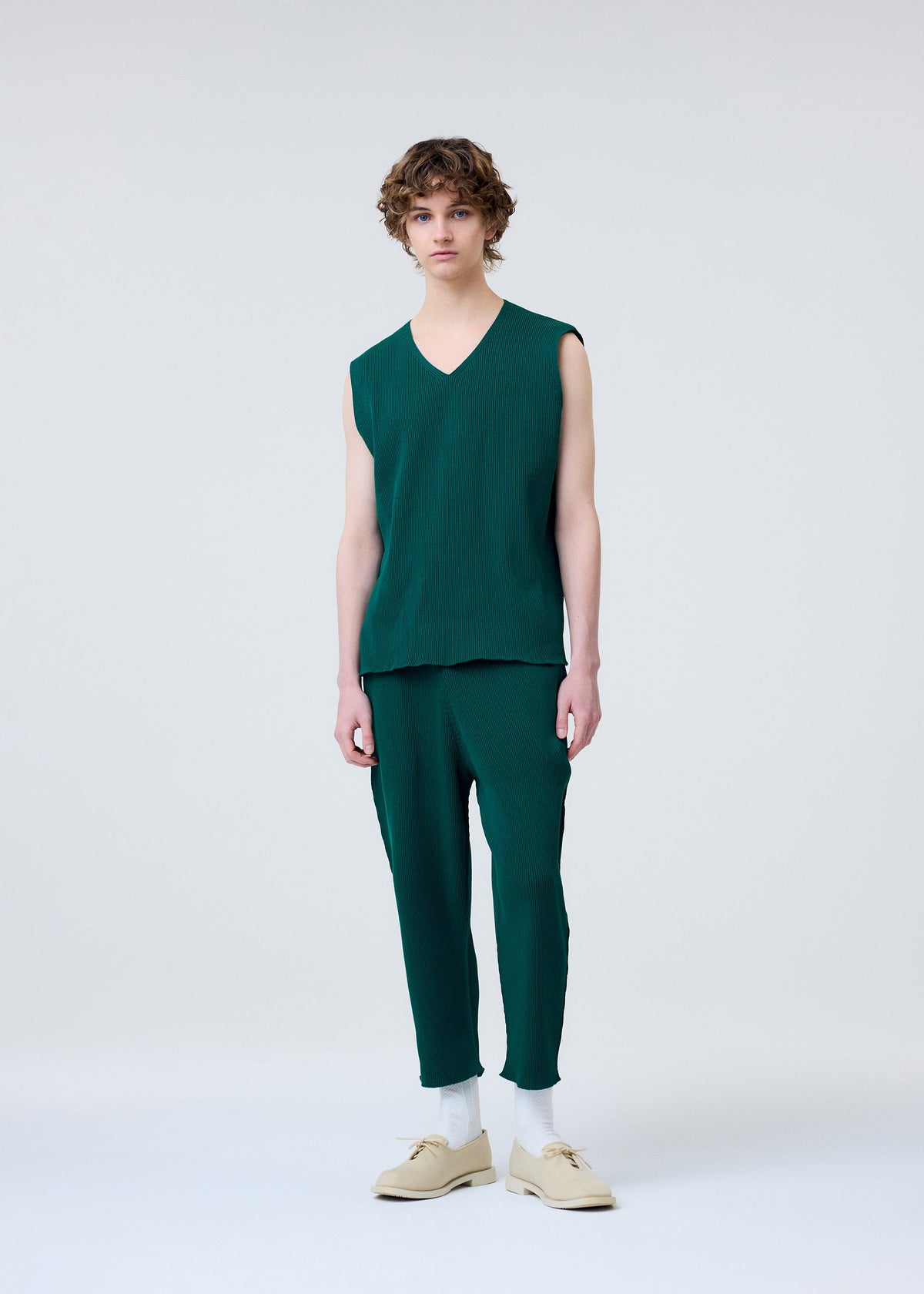 A model wears the HOMME PLISSÉ ISSEY MIYAKE BASIC KNIT clothing.