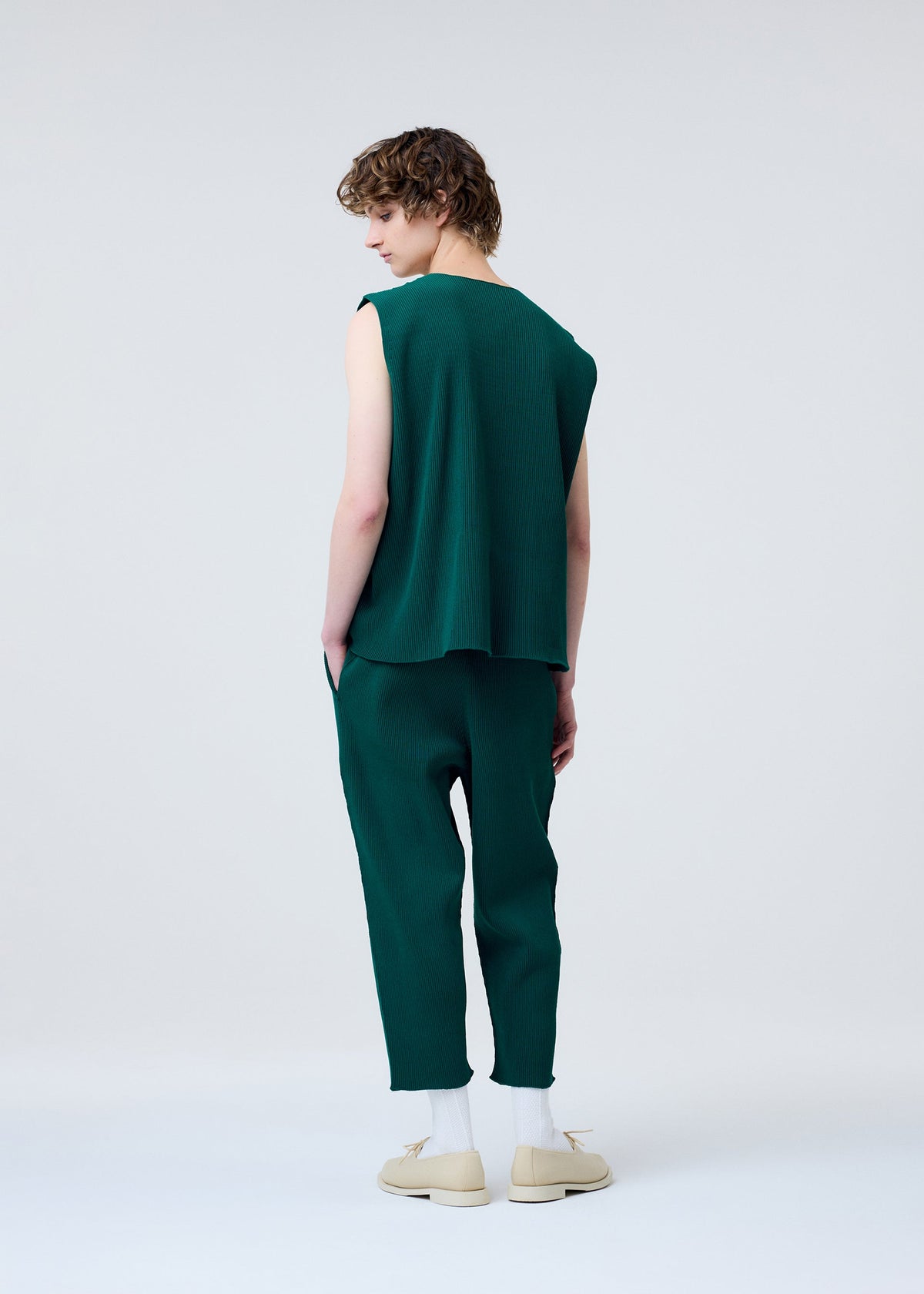 A model wears the HOMME PLISSÉ ISSEY MIYAKE BASIC KNIT clothing.