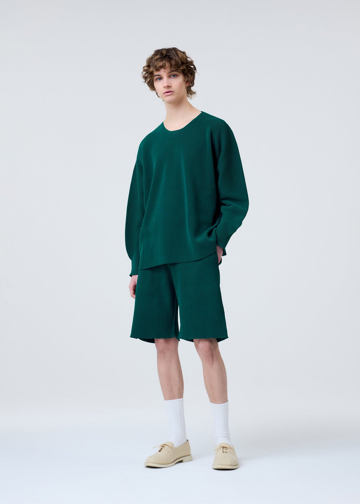 A model wears the HOMME PLISSÉ ISSEY MIYAKE BASIC KNIT clothing.
