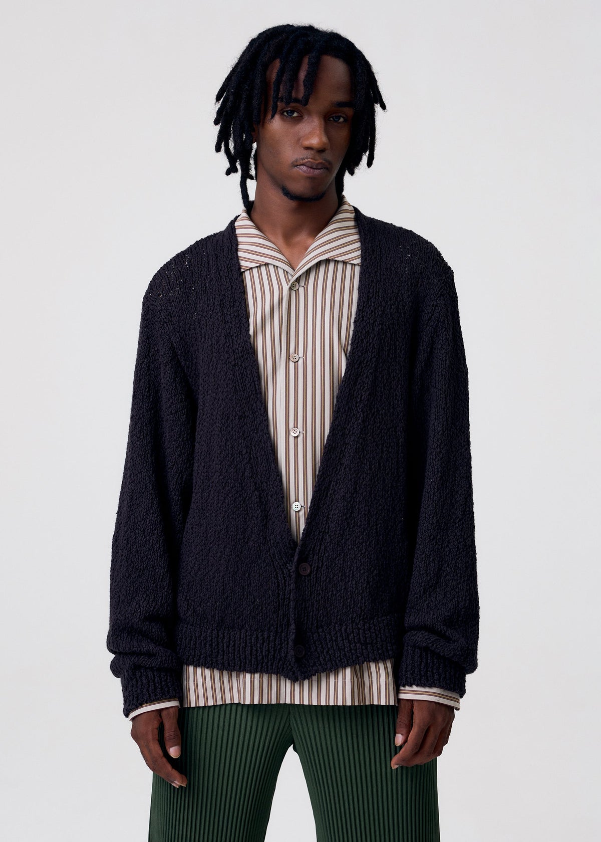 A model wears the HOMME PLISSÉ ISSEY MIYAKE RISOTTO KNIT cardigan.