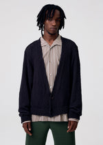 A model wears the HOMME PLISSÉ ISSEY MIYAKE RISOTTO KNIT cardigan.