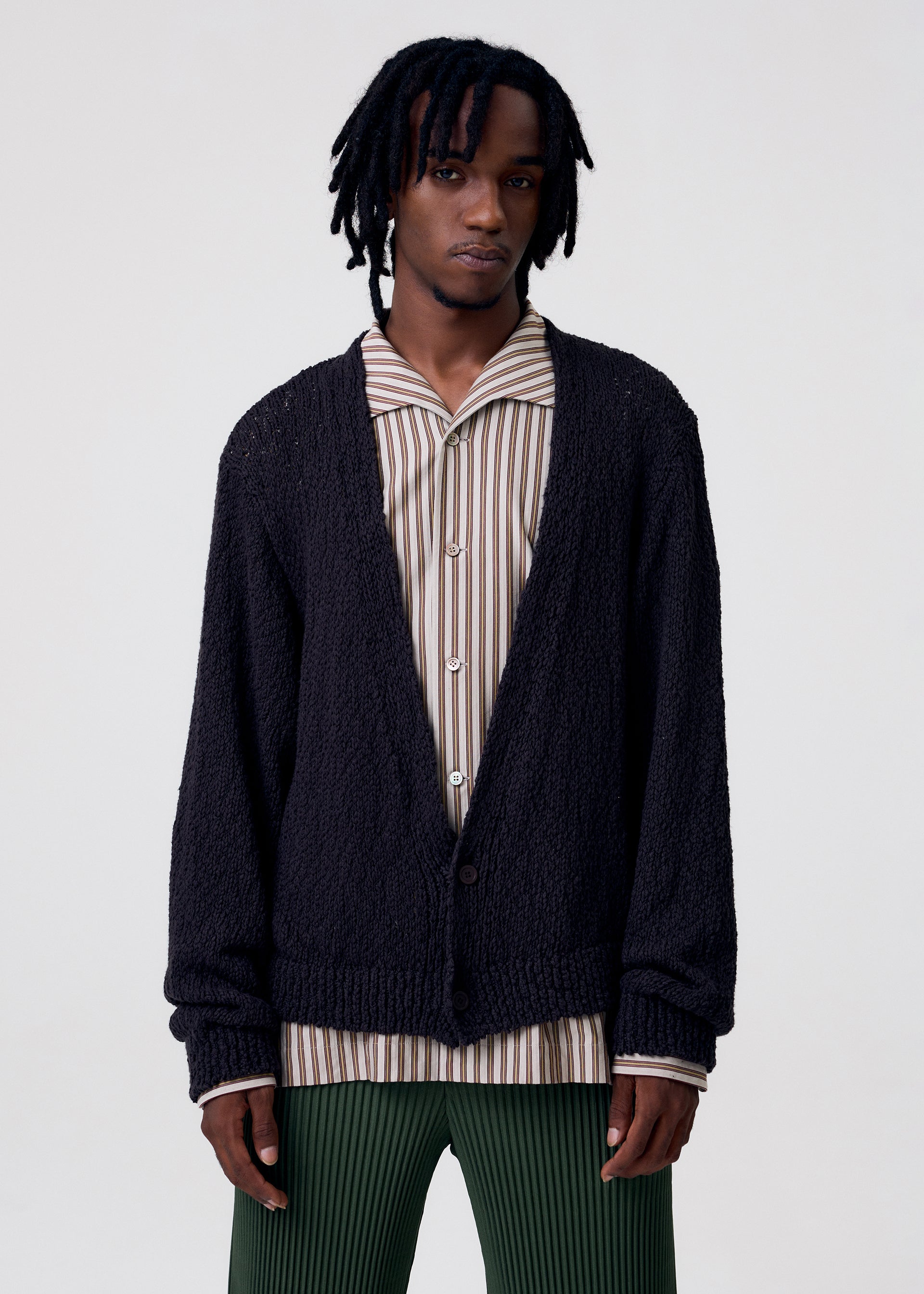A model wears the HOMME PLISSÉ ISSEY MIYAKE RISOTTO KNIT cardigan.