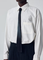 A model wears the HOMME PLISSÉ ISSEY MIYAKE IN THE SHADOW PLEATS TIE in-the-shadow-pleats-tie-tie-shadow-black.