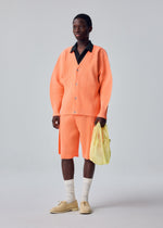A model wears the HOMME PLISSÉ ISSEY MIYAKE MESH PLEATS BAG mesh-pleats-bag-tote-yellow.