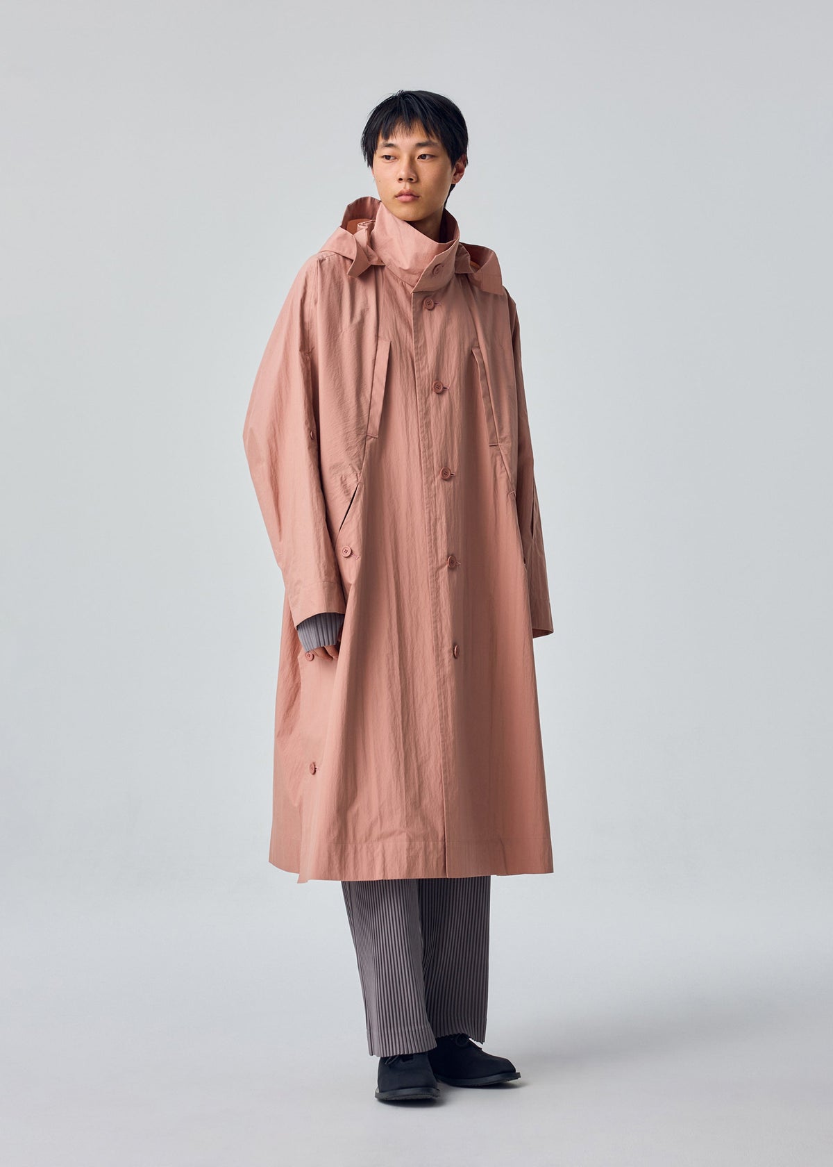 A model wears the HOMME PLISSÉ ISSEY MIYAKE SLIT COAT slit-coat-coat-green.