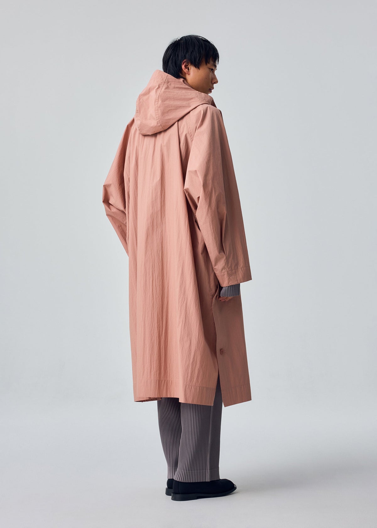 A model wears the HOMME PLISSÉ ISSEY MIYAKE SLIT COAT slit-coat-coat-green.