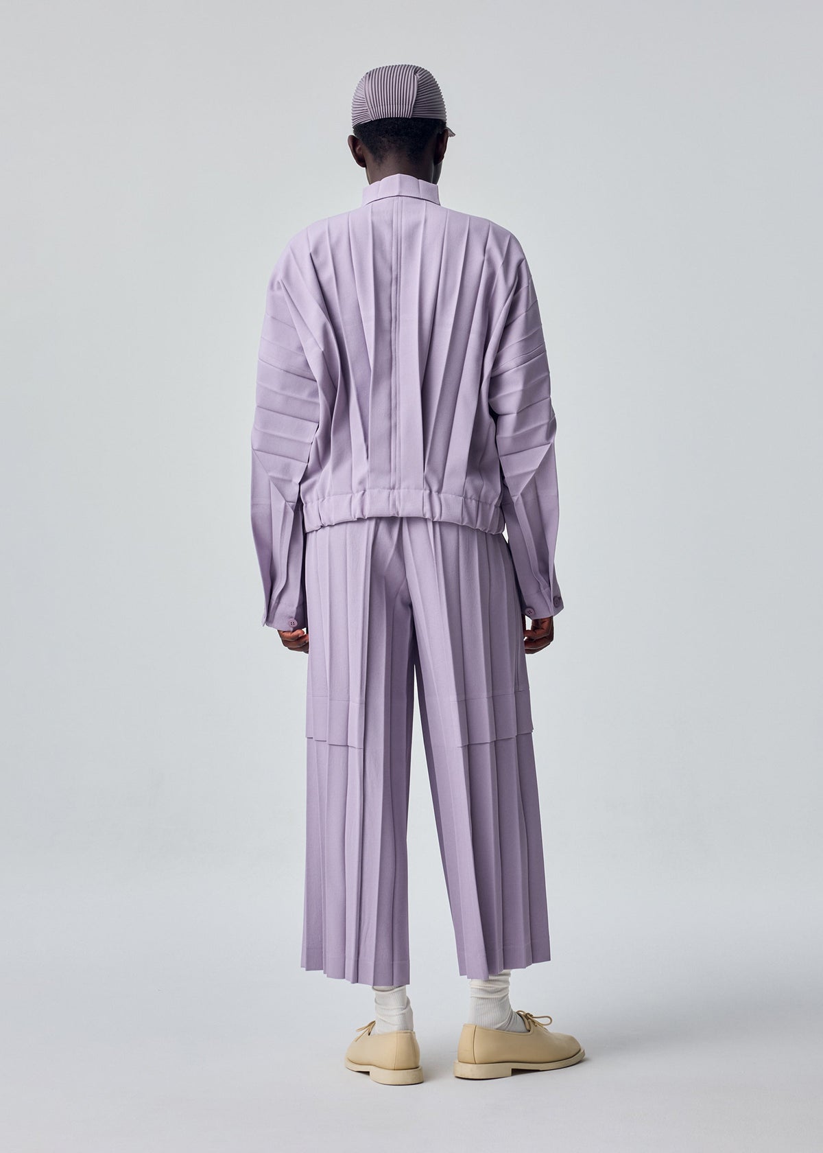 A model wears the HOMME PLISSÉ ISSEY MIYAKE EDGE ENSEMBLE edge-ensemble-jacket-lavender.