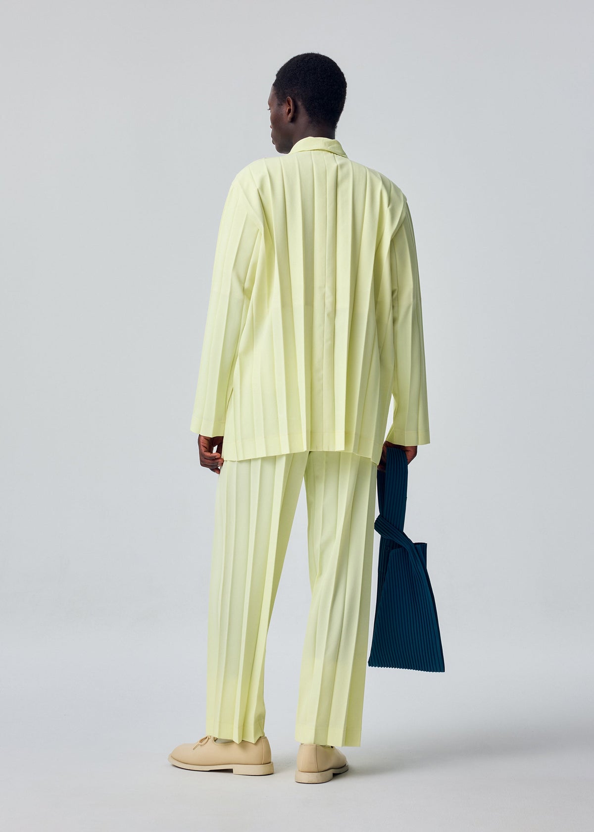 A model wears the HOMME PLISSÉ ISSEY MIYAKE EDGE ENSEMBLE edge-ensemble-jacket-lavender-1.