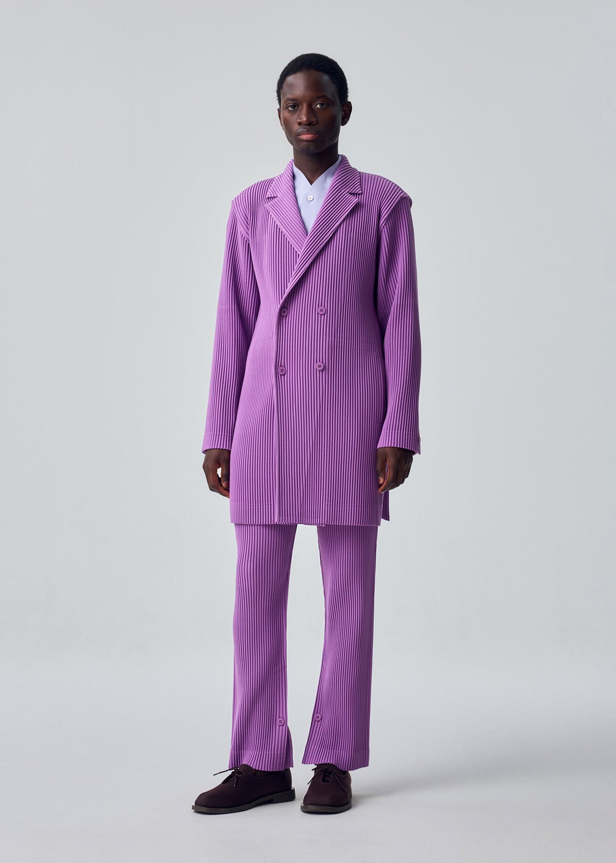 A model wears the HOMME PLISSÉ ISSEY MIYAKE KERSEY PLEATS kersey-pleats-long-jacket-purple.