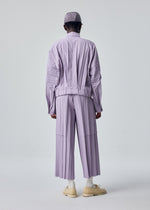 A model wears the HOMME PLISSÉ ISSEY MIYAKE EDGE ENSEMBLE edge-ensemble-trousers-yellow-1.