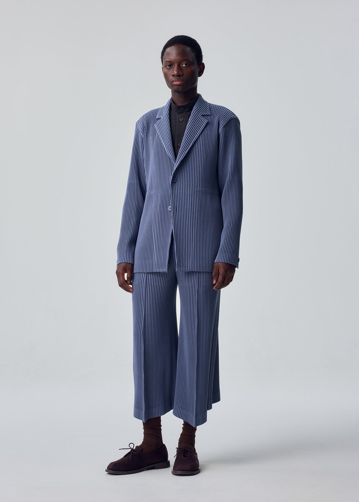 A model wears the HOMME PLISSÉ ISSEY MIYAKE KERSEY PLEATS kersey-pleats-cropped-trousers-purple.