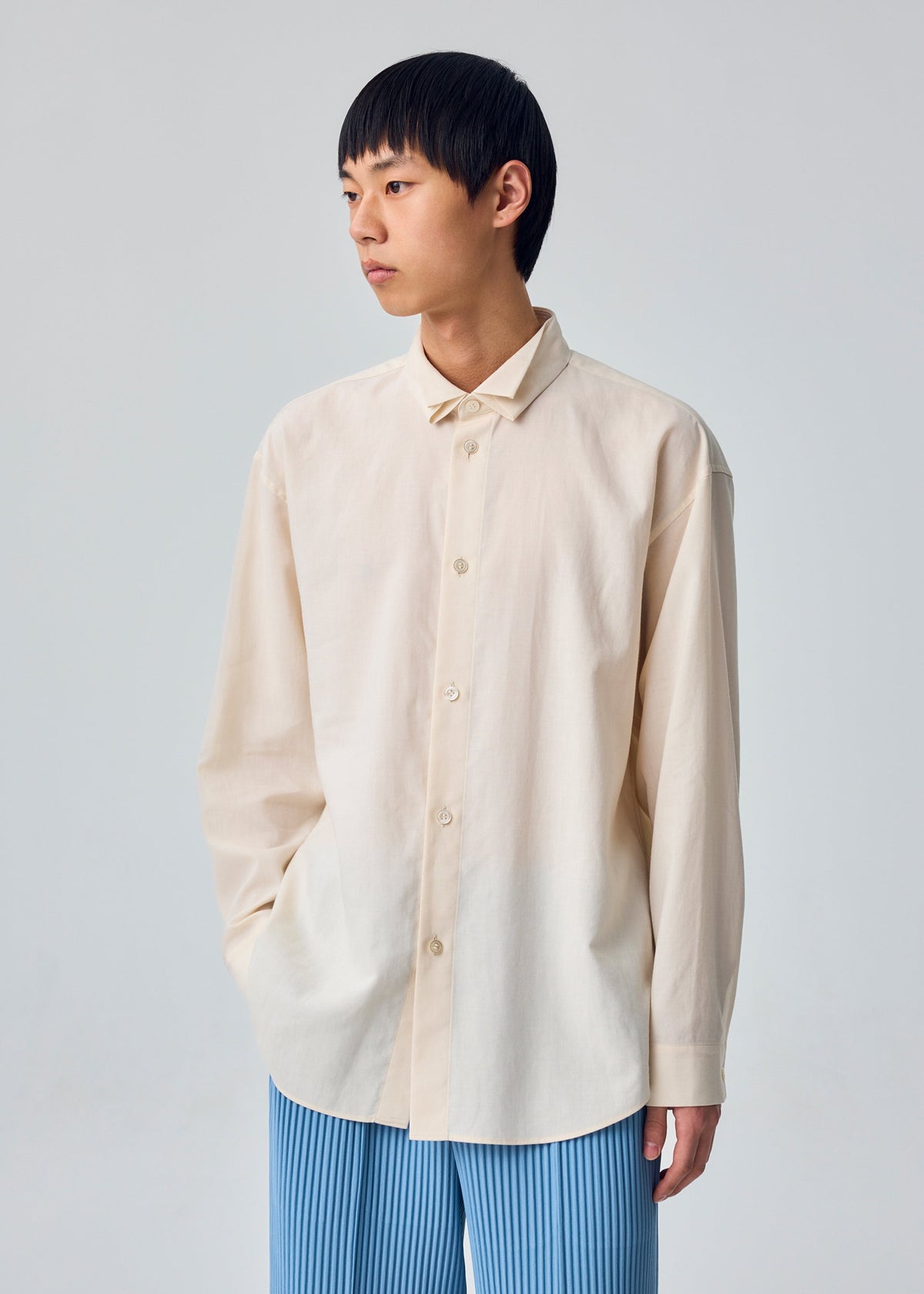A model wears the HOMME PLISSÉ ISSEY MIYAKE PL RAMIE SHIRT pl-ramie-shirt-origami-collar-shirt-beige.