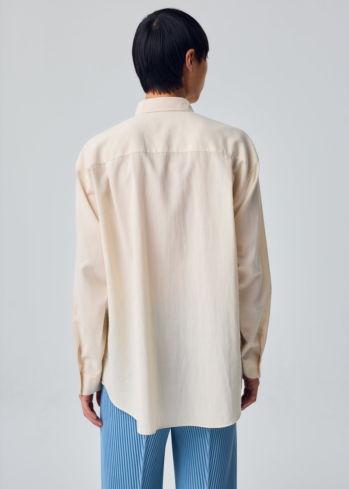 A model wears the HOMME PLISSÉ ISSEY MIYAKE PL RAMIE SHIRT pl-ramie-shirt-origami-collar-shirt-beige.