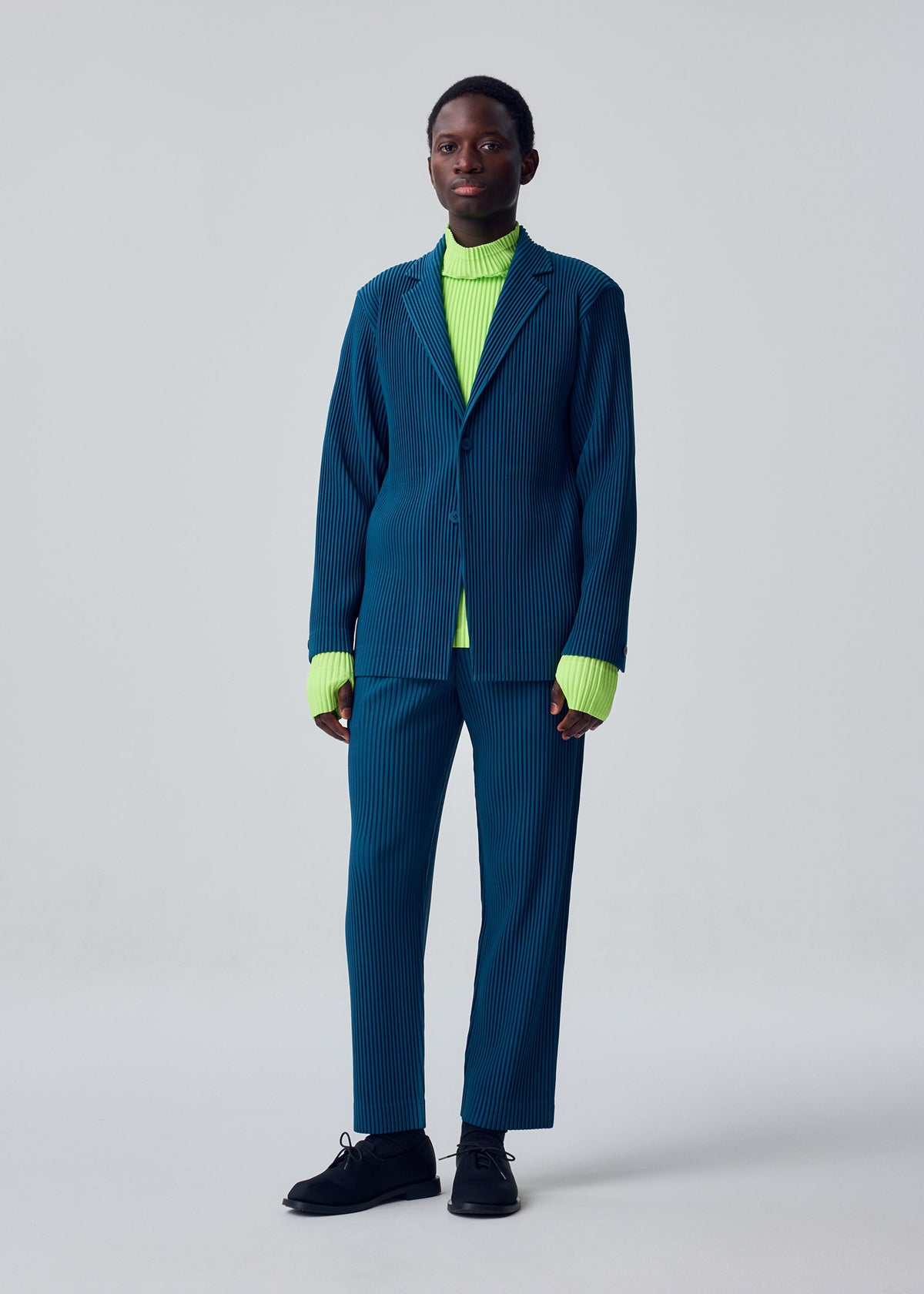 A model wears the HOMME PLISSÉ ISSEY MIYAKE TAILORED PLEATS 1 tailored-pleats-1-jacket-shadow-blue.