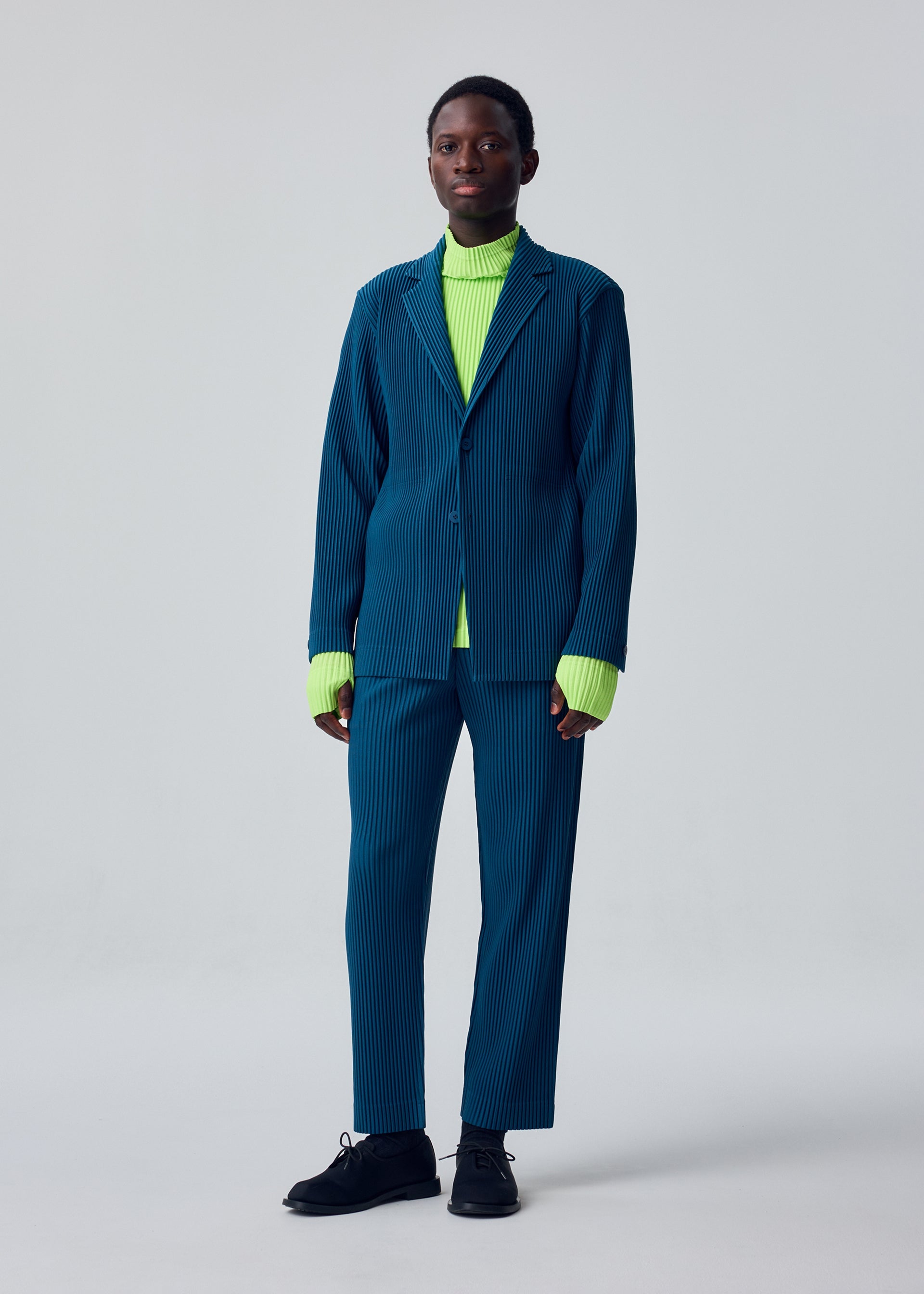 A model wears the HOMME PLISSÉ ISSEY MIYAKE TAILORED PLEATS 1 tailored-pleats-1-jacket-shadow-blue.