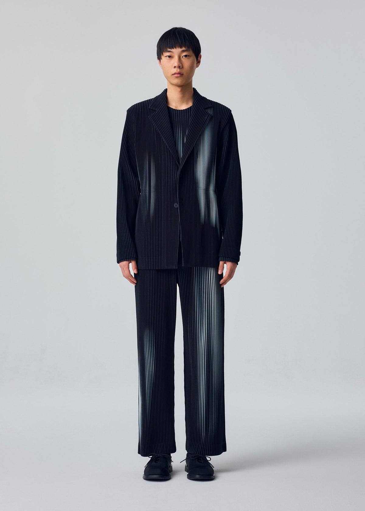 A model wears the HOMME PLISSÉ ISSEY MIYAKE IN THE SHADOW in-the-shadow-jacket-shadow-black.