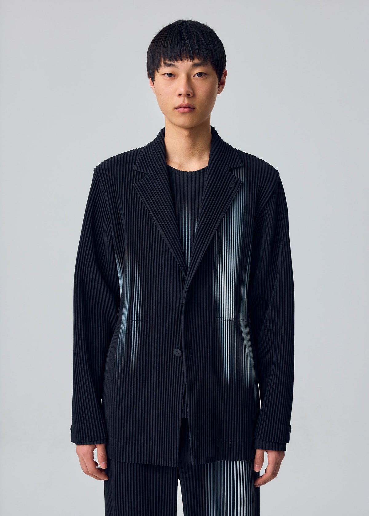 A model wears the HOMME PLISSÉ ISSEY MIYAKE IN THE SHADOW in-the-shadow-jacket-shadow-black.
