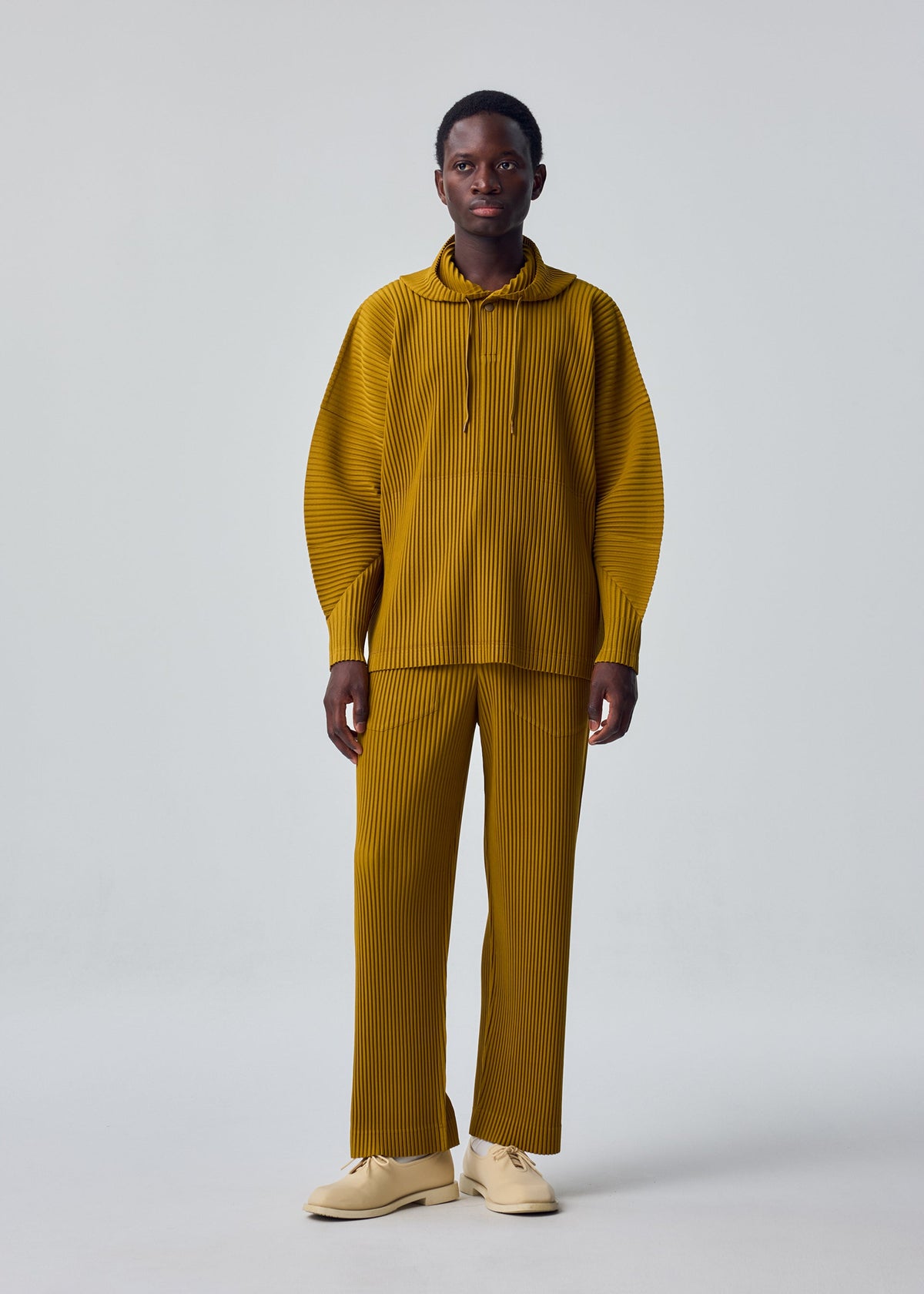A model wears the HOMME PLISSÉ ISSEY MIYAKE MONTHLY COLORS : OCTOBER monthly-colors-october-classic-cut-trousers-black.