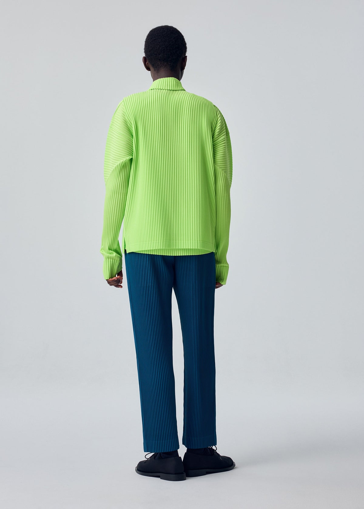 A model wears the HOMME PLISSÉ ISSEY MIYAKE TAILORED PLEATS 1 tailored-pleats-1-trousers-shadow-blue.