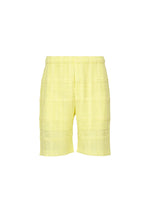 A product shot of the HOMME PLISSÉ ISSEY MIYAKE LACE GRID PLEATS shorts in yellow.