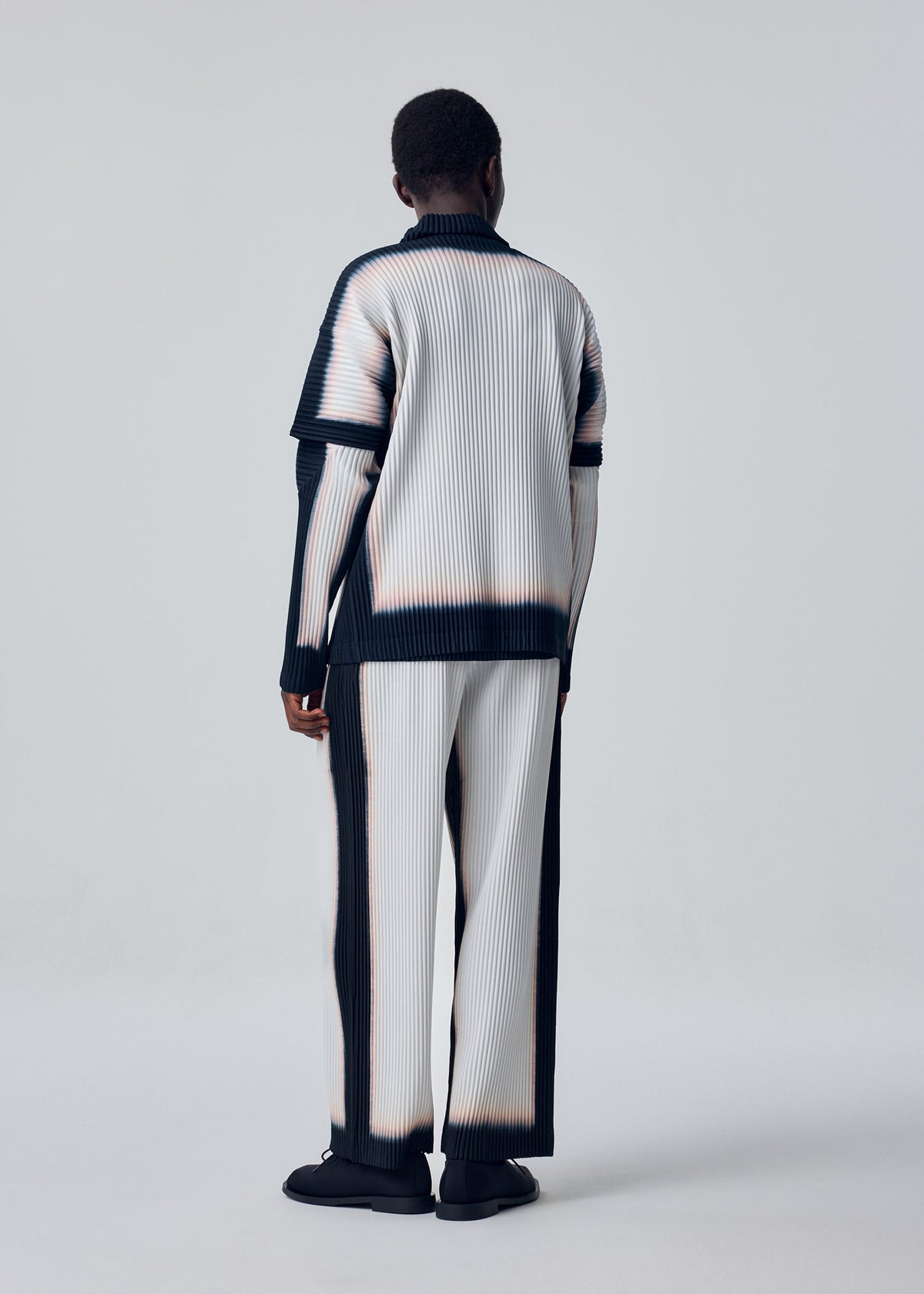 A model wears the HOMME PLISSÉ ISSEY MIYAKE FRAMEWORK : CHUSEN framework-chusen-trousers-white.