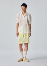 A model wears the HOMME PLISSÉ ISSEY MIYAKE LACE GRID PLEATS lace-grid-pleats-shirt-white.