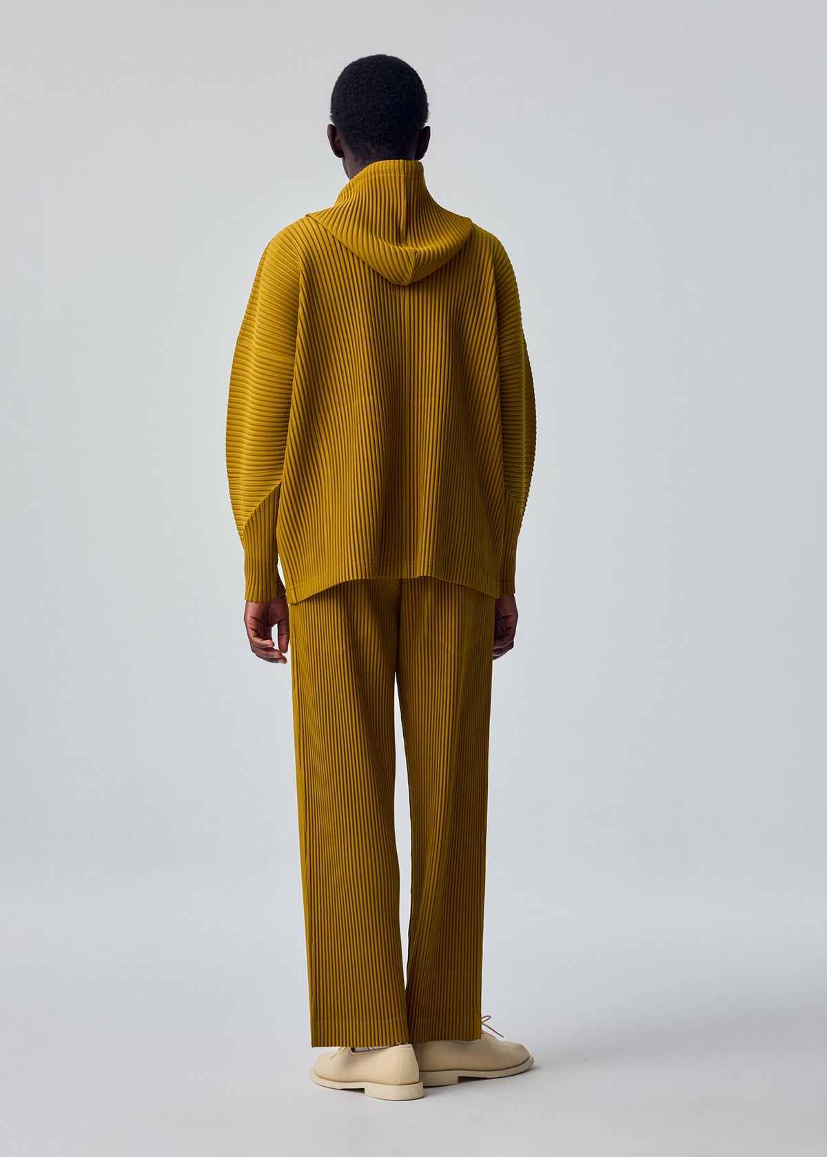 A model wears the HOMME PLISSÉ ISSEY MIYAKE MONTHLY COLORS : OCTOBER monthly-colors-october-hooded-top-black.