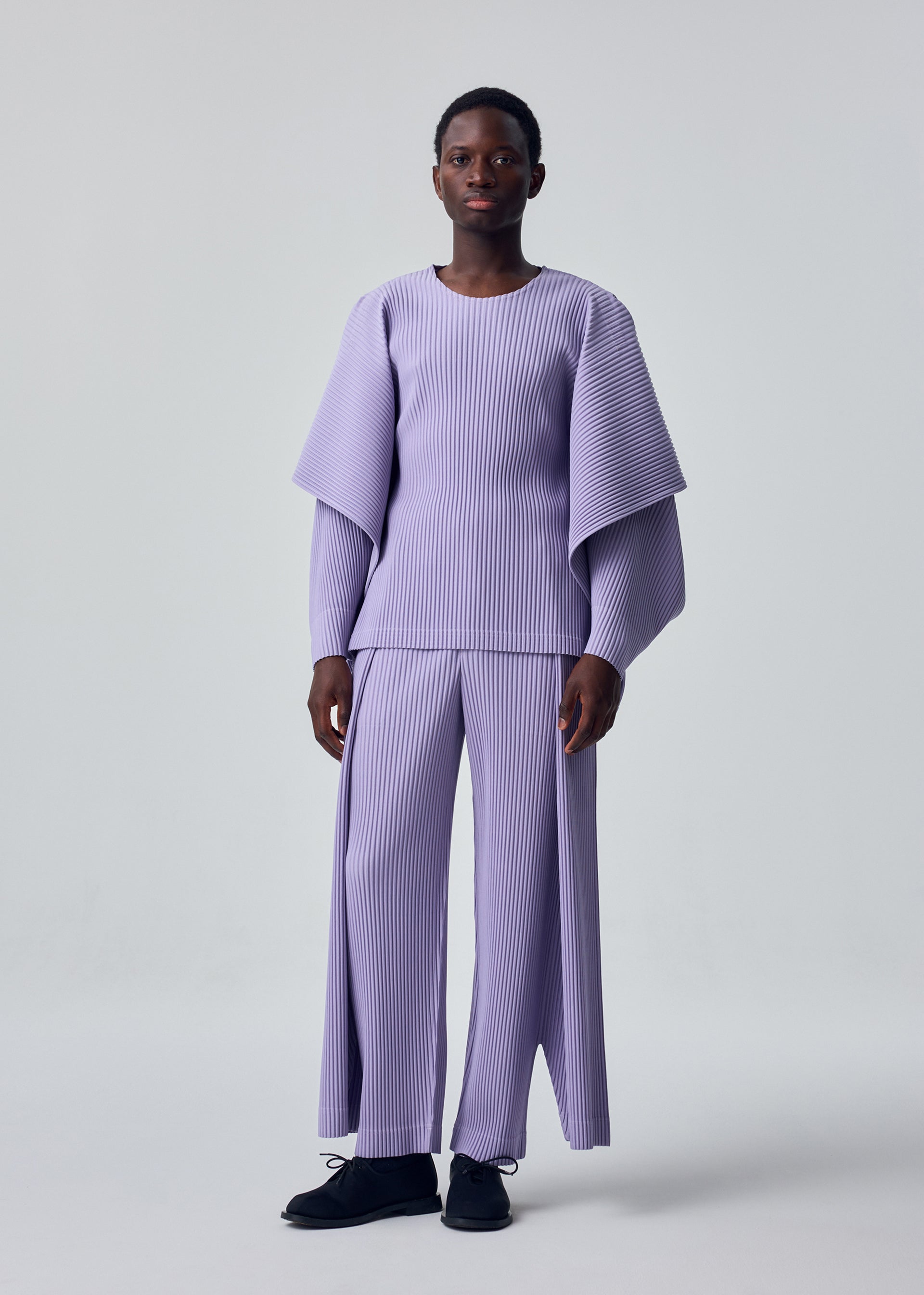 A model wears the HOMME PLISSÉ ISSEY MIYAKE MOTION BLUR top.