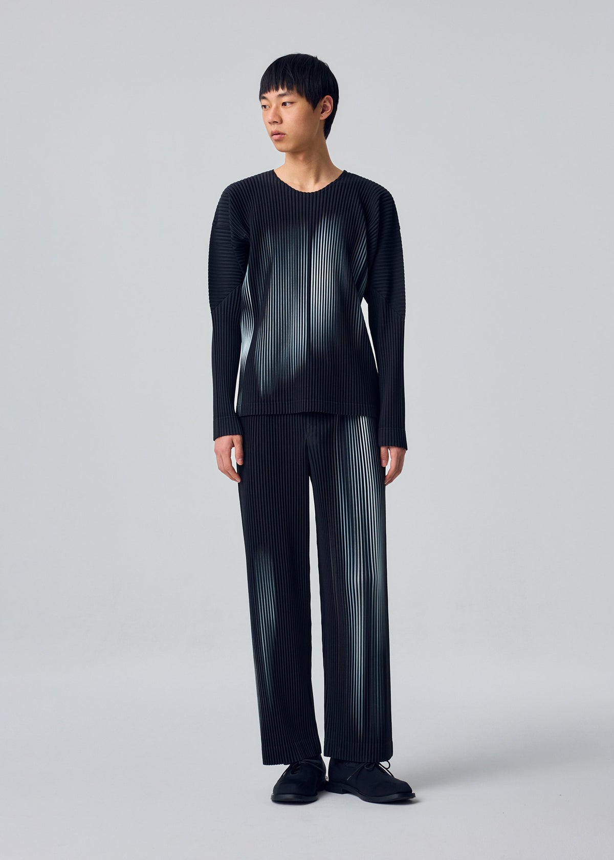 A model wears the HOMME PLISSÉ ISSEY MIYAKE IN THE SHADOW in-the-shadow-top-shadow-black.