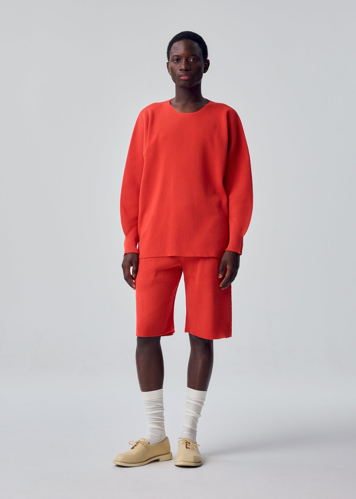 A model wears the HOMME PLISSÉ ISSEY MIYAKE BASIC KNIT basic-knit-long-sleeved-jersey-top-light-grey.