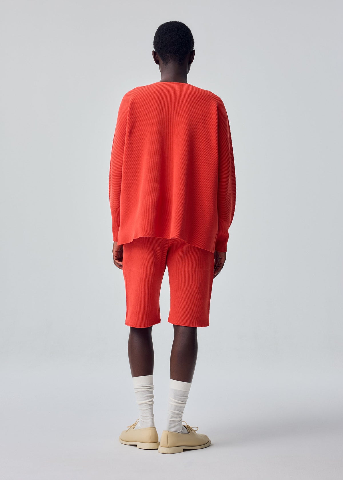 A model wears the HOMME PLISSÉ ISSEY MIYAKE BASIC KNIT basic-knit-long-sleeved-jersey-top-light-grey.