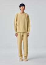 A model wears the HOMME PLISSÉ ISSEY MIYAKE RUSTIC KNIT rustic-knit-top-yellow-beige.