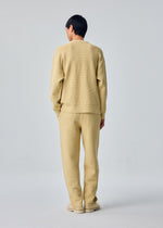 A model wears the HOMME PLISSÉ ISSEY MIYAKE RUSTIC KNIT rustic-knit-top-yellow-beige.