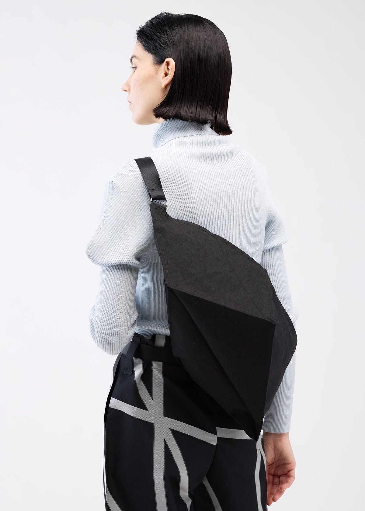 A model wears the 132 5. ISSEY MIYAKE PARALLELEPIPED bag.