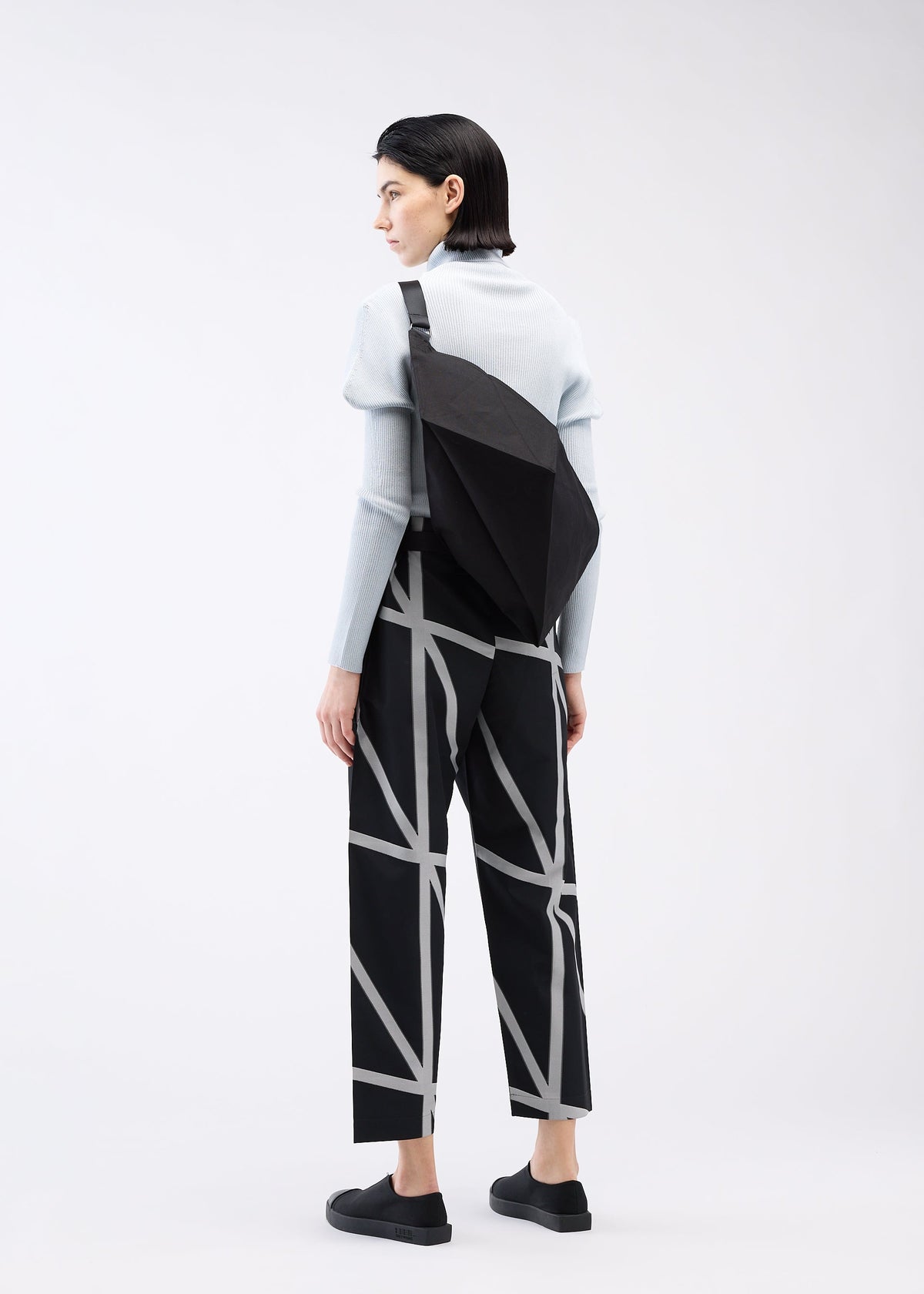 A model wears the 132 5. ISSEY MIYAKE PARALLELEPIPED bag.