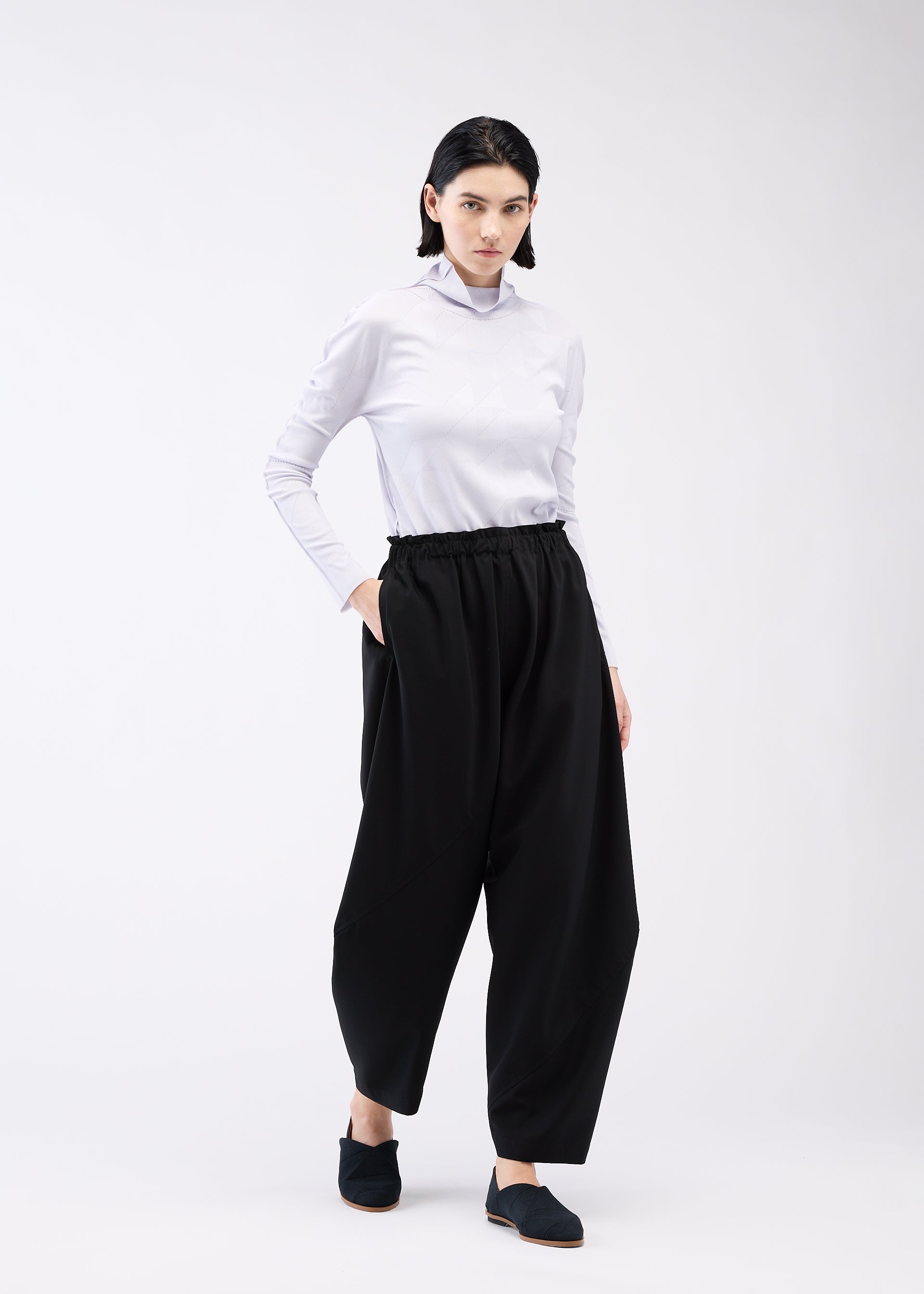 A model wears the 132 5. ISSEY MIYAKE PARALLEL WRAP trousers.