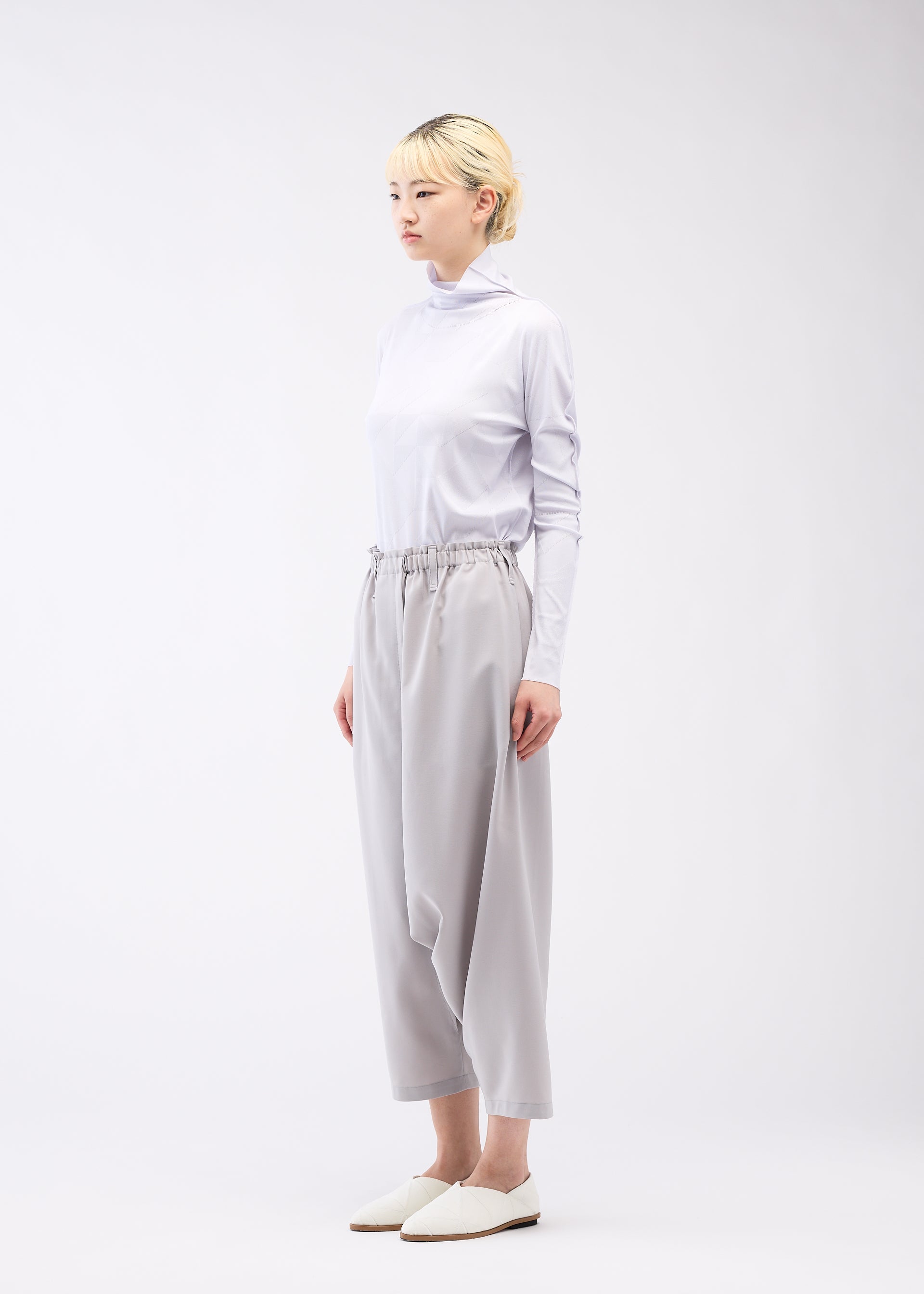 A model wears the 132 5. ISSEY MIYAKE SEAMLESS 1 trousers.